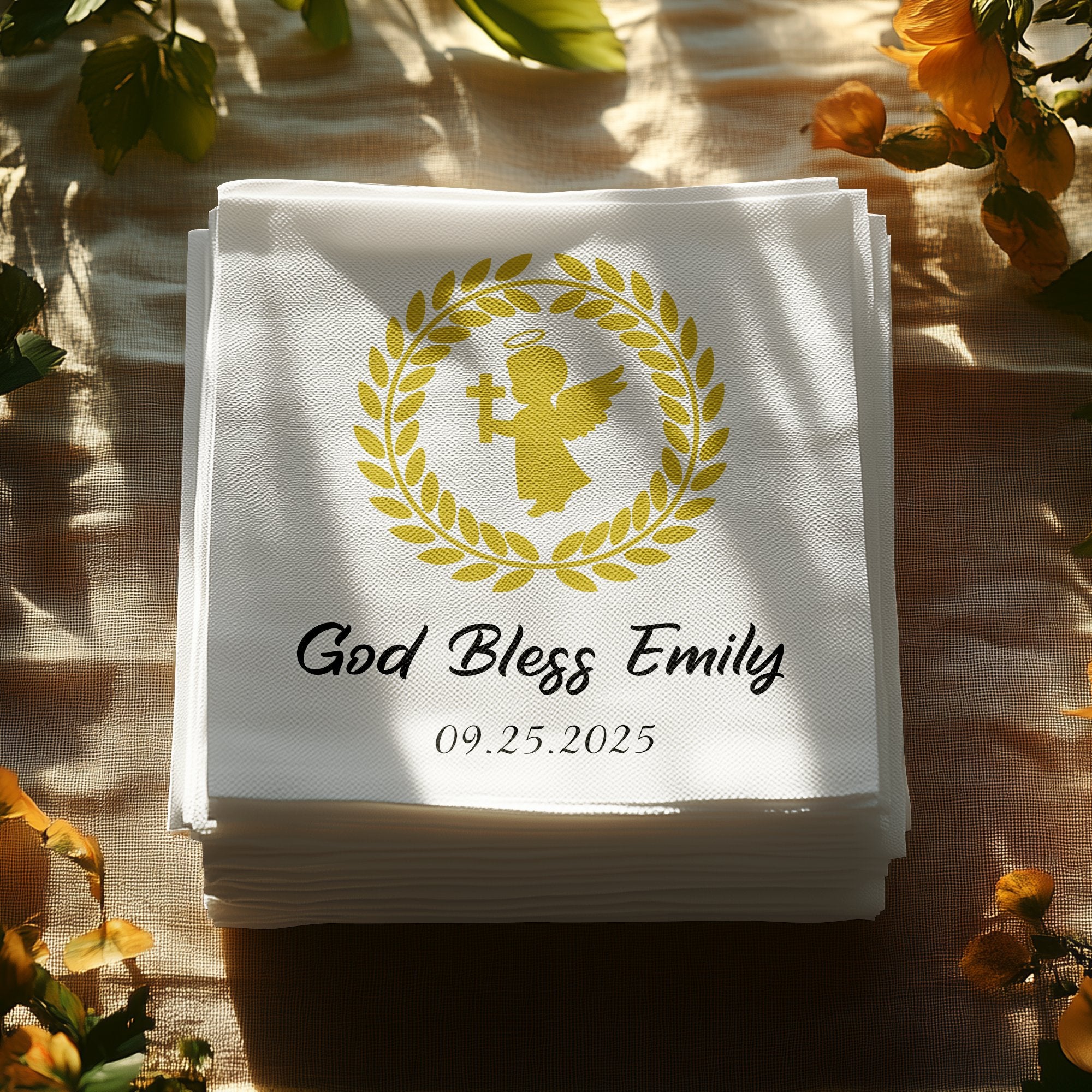 White linen napkin with gold angel emblem, "God Bless Emily," and date.