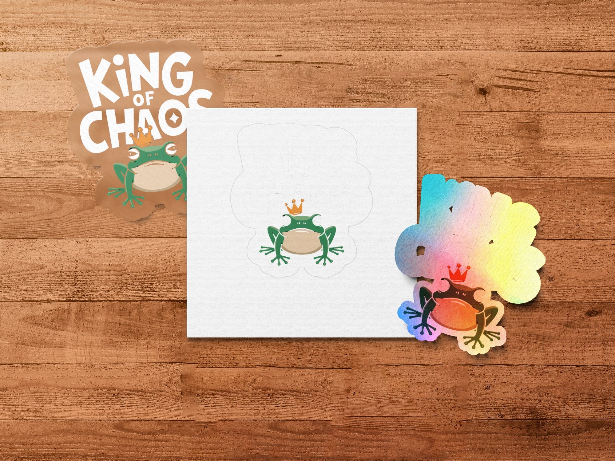 Frog stickers and card with "King of Chaos" text on a wooden background.