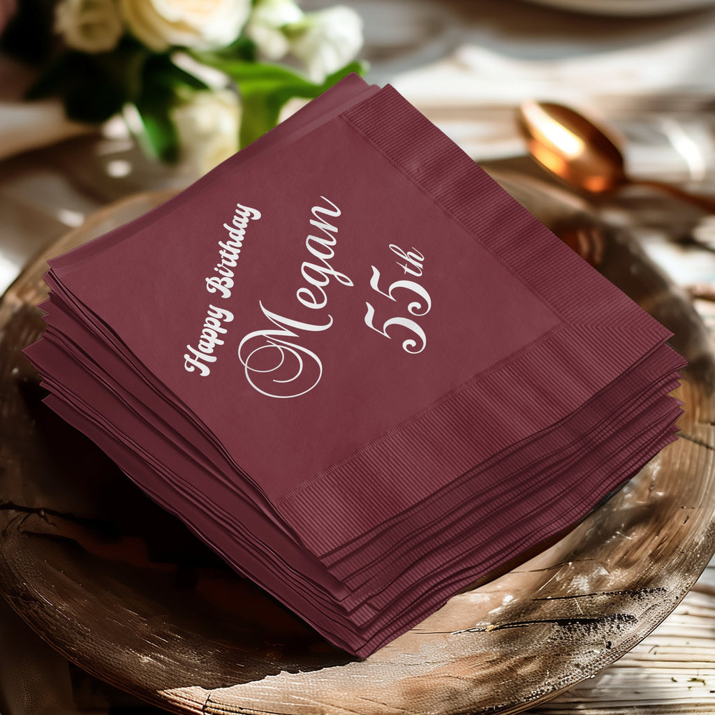 Burgundy napkins stacked, with "Happy Birthday Megan 55th" in white text.