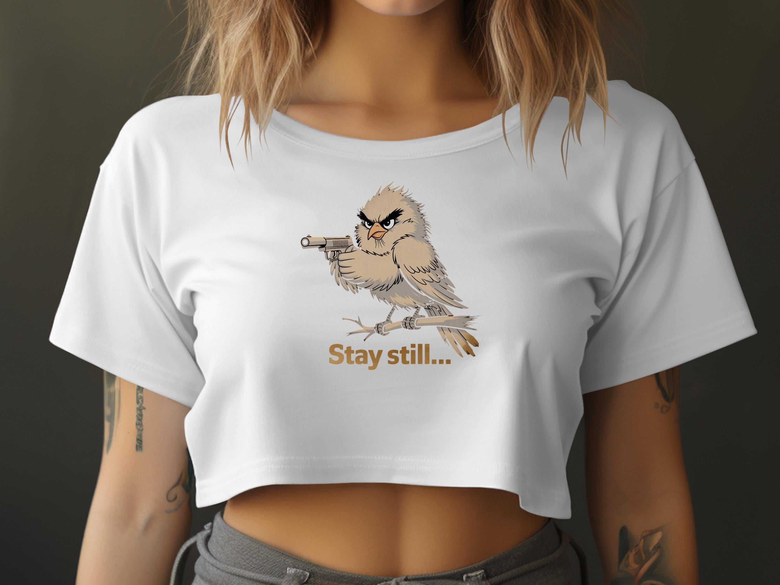 White crop top with illustration of bird holding a gun and text "Stay still".