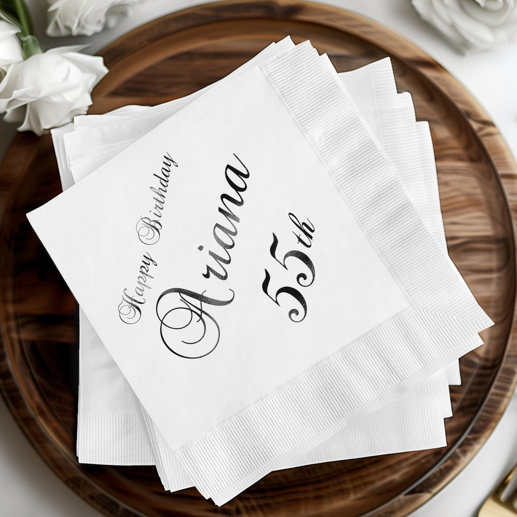 White cocktail napkins with "Happy Birthday Ariana 55th" in script.