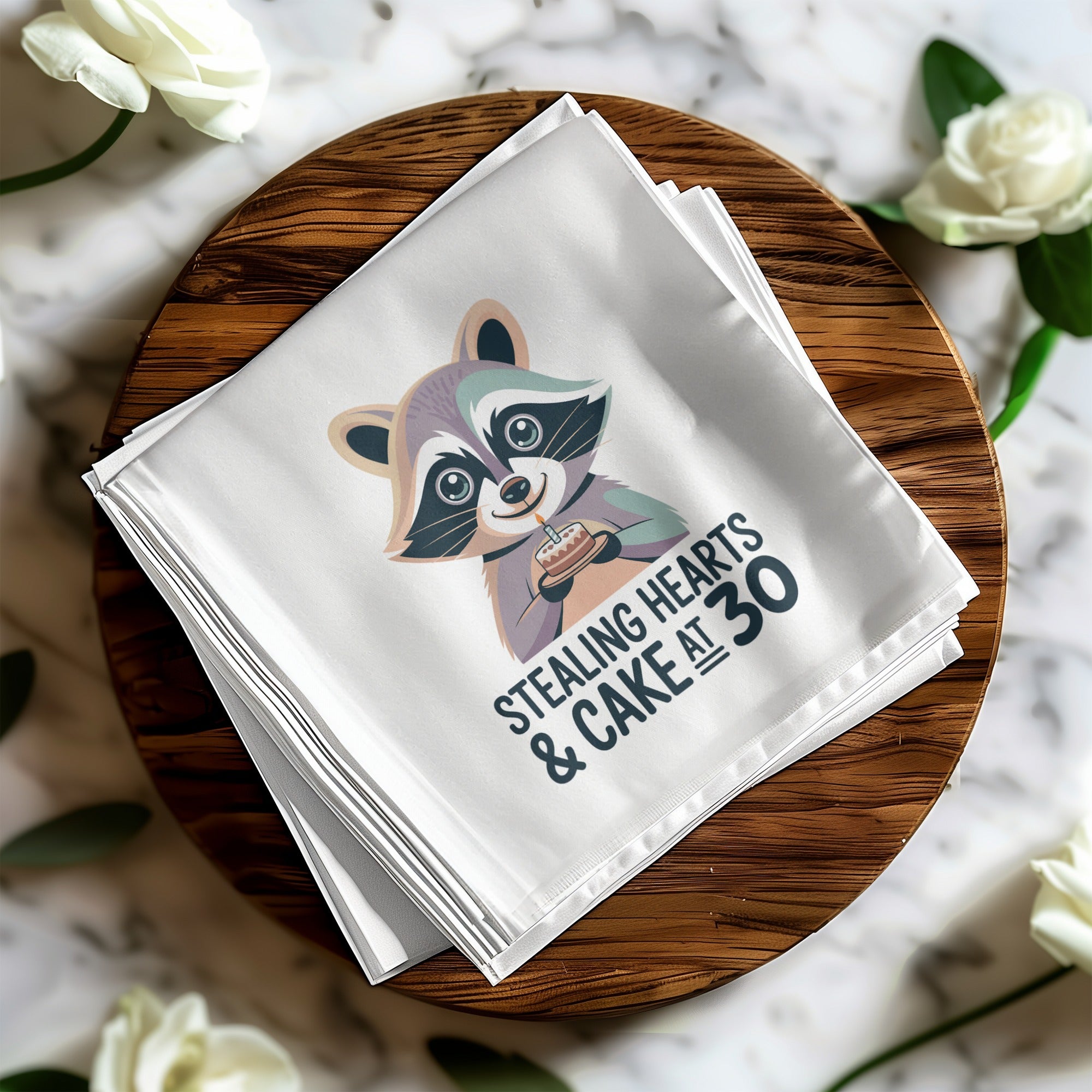 White napkin with raccoon illustration and "Stealing Hearts & Cake at 30" text.