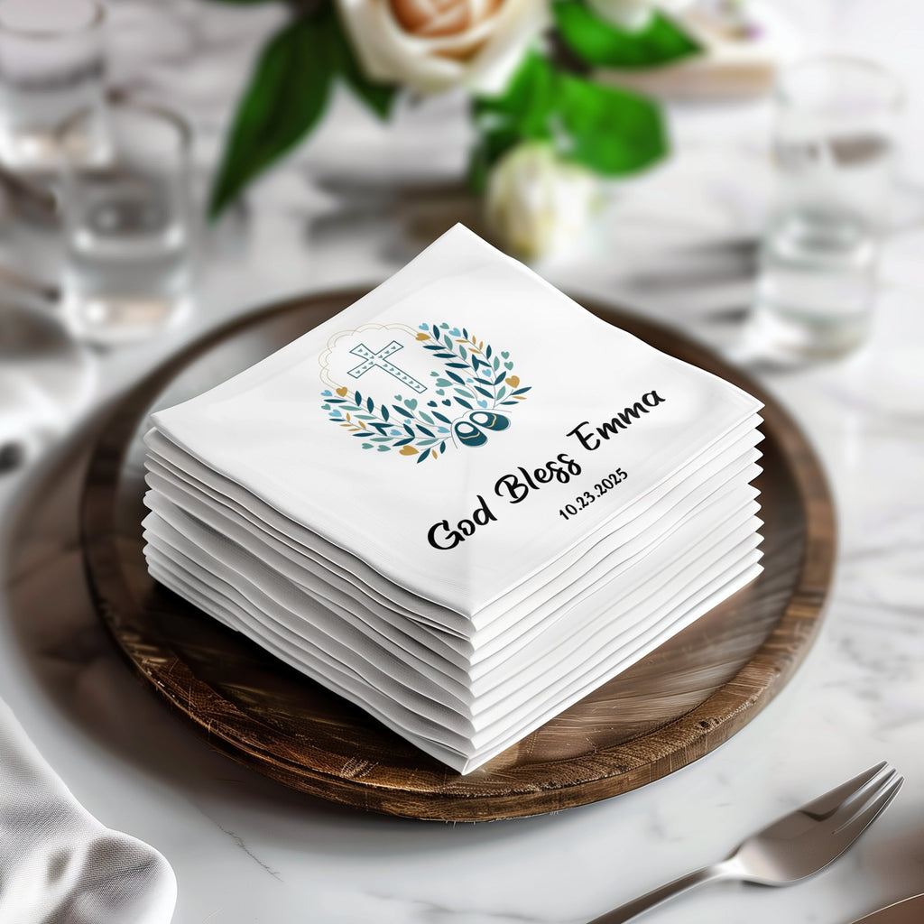 White baptism napkins with "God Bless Emma 10.23.2025" and a cross design.