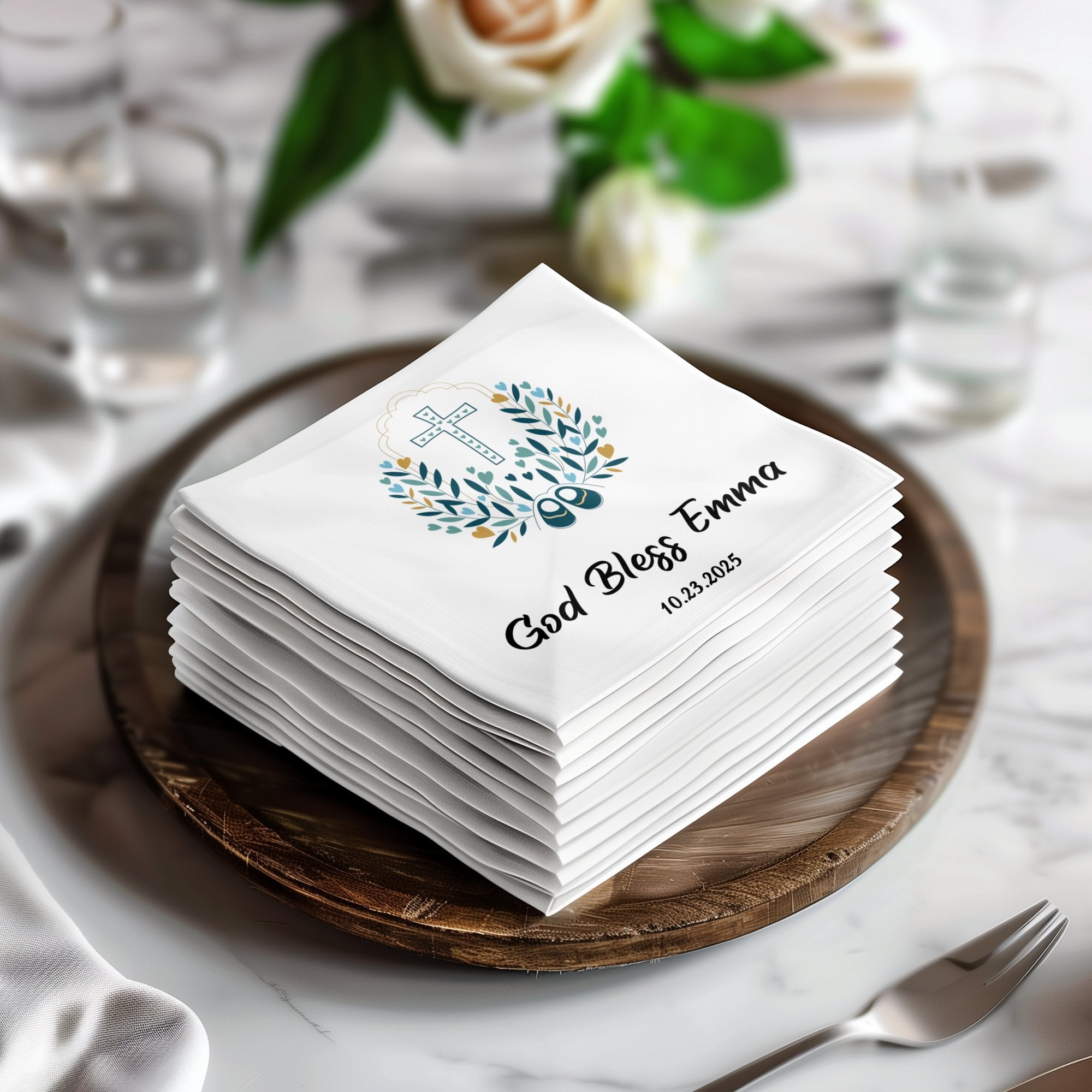 White baptism napkins with "God Bless Emma 10.23.2025" and a cross design.