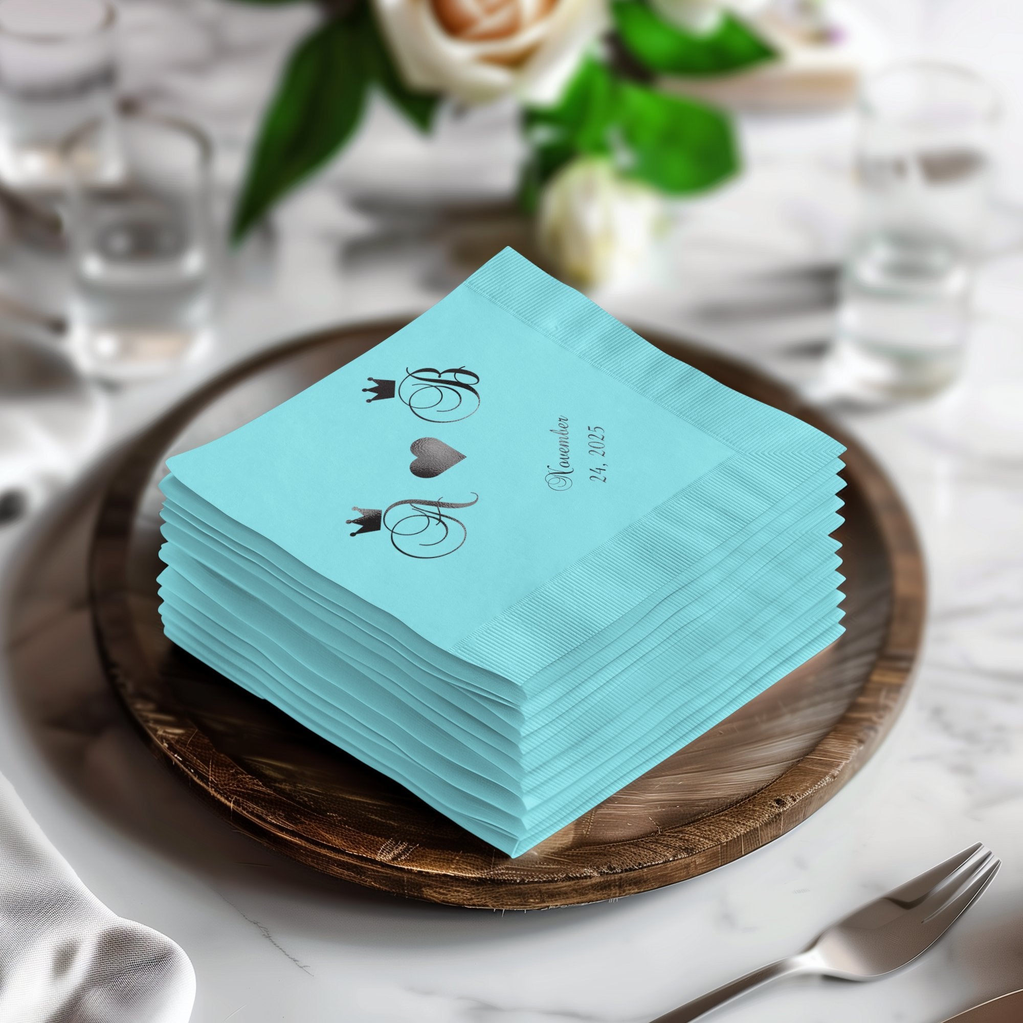 Stack of teal wedding cocktail napkins with monogram and date.