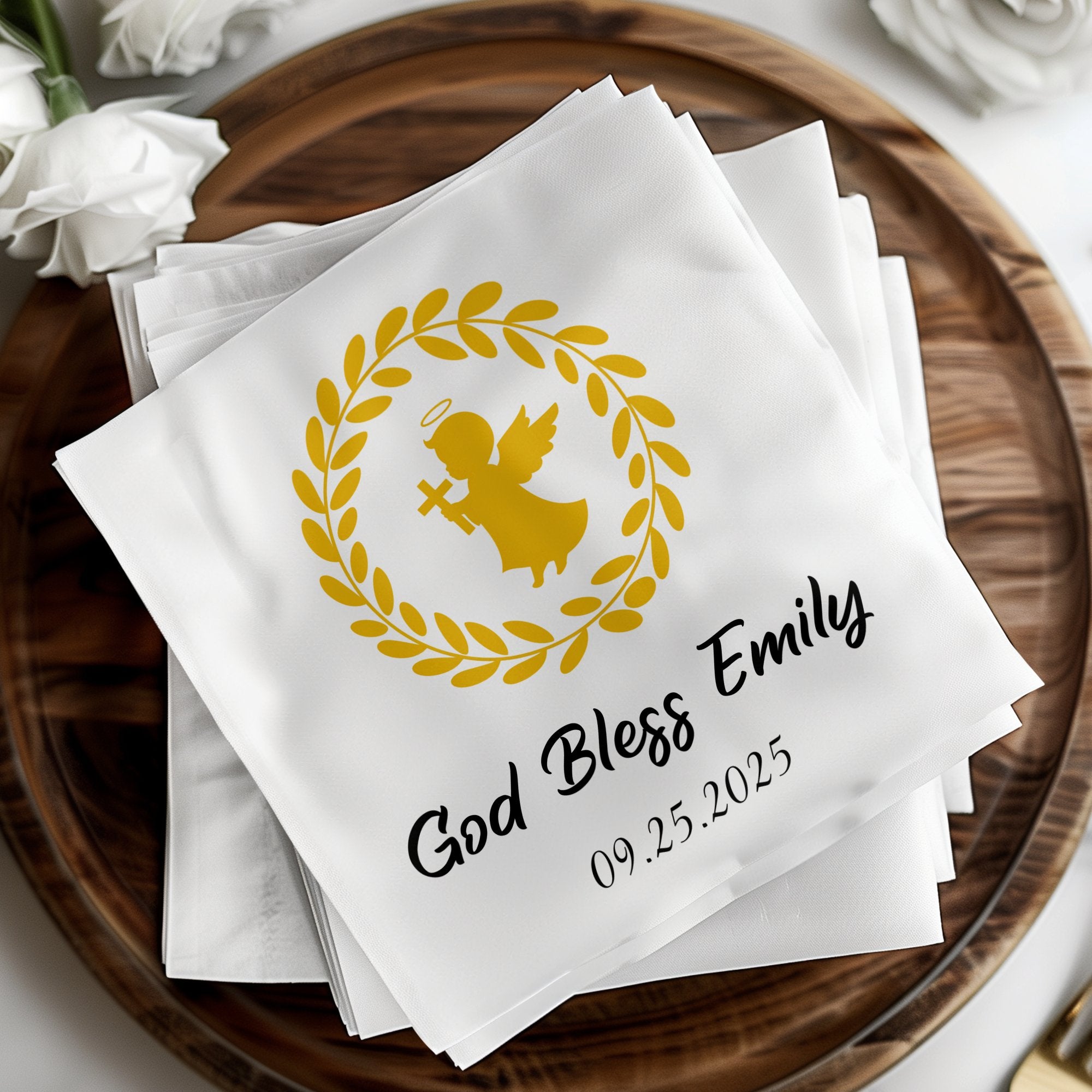 White napkin with gold angel, wreath, and text "God Bless Emily 09.25.2025".