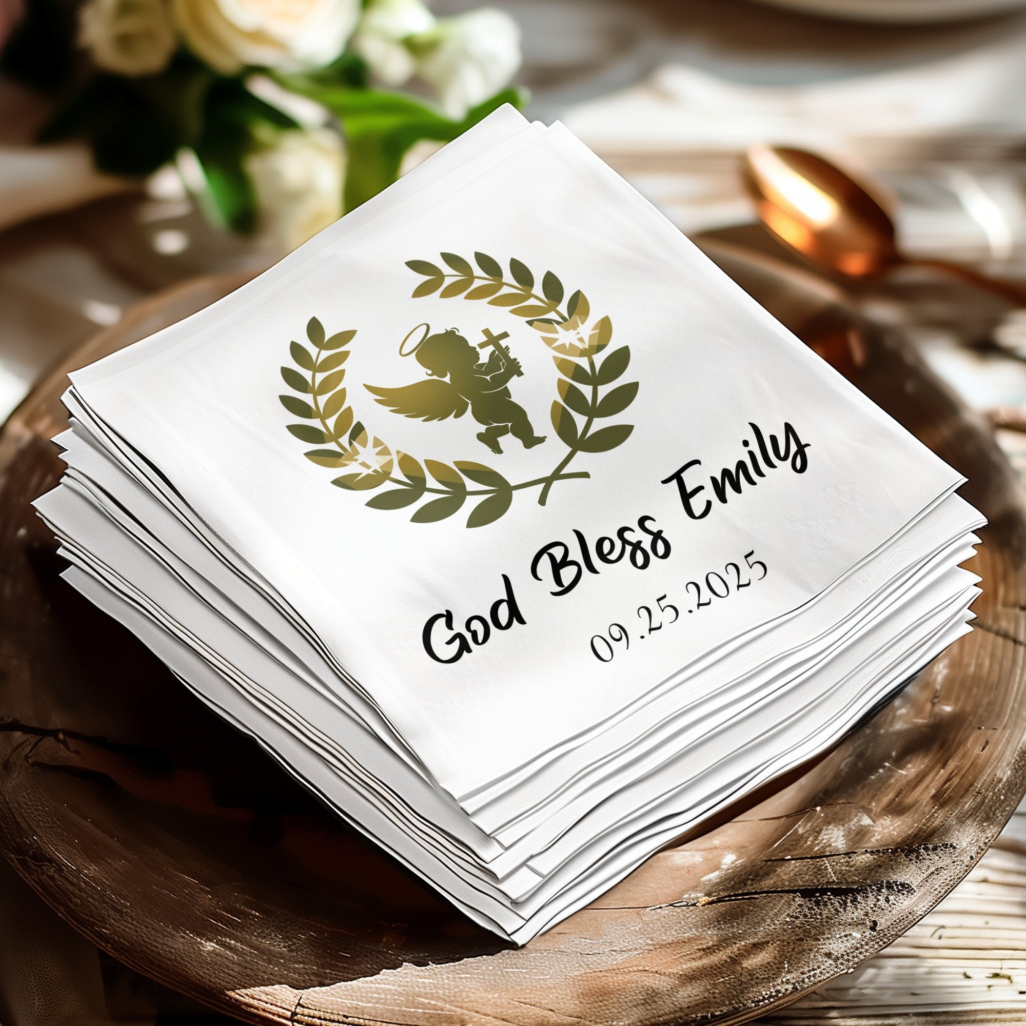 White napkins with gold angel, laurel wreath, and personalized text: God Bless Emily 09.25.2025.