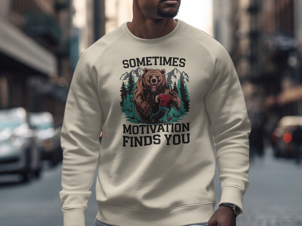 Cream sweatshirt with bear and hiker graphic and text: "Sometimes Motivation Finds You".