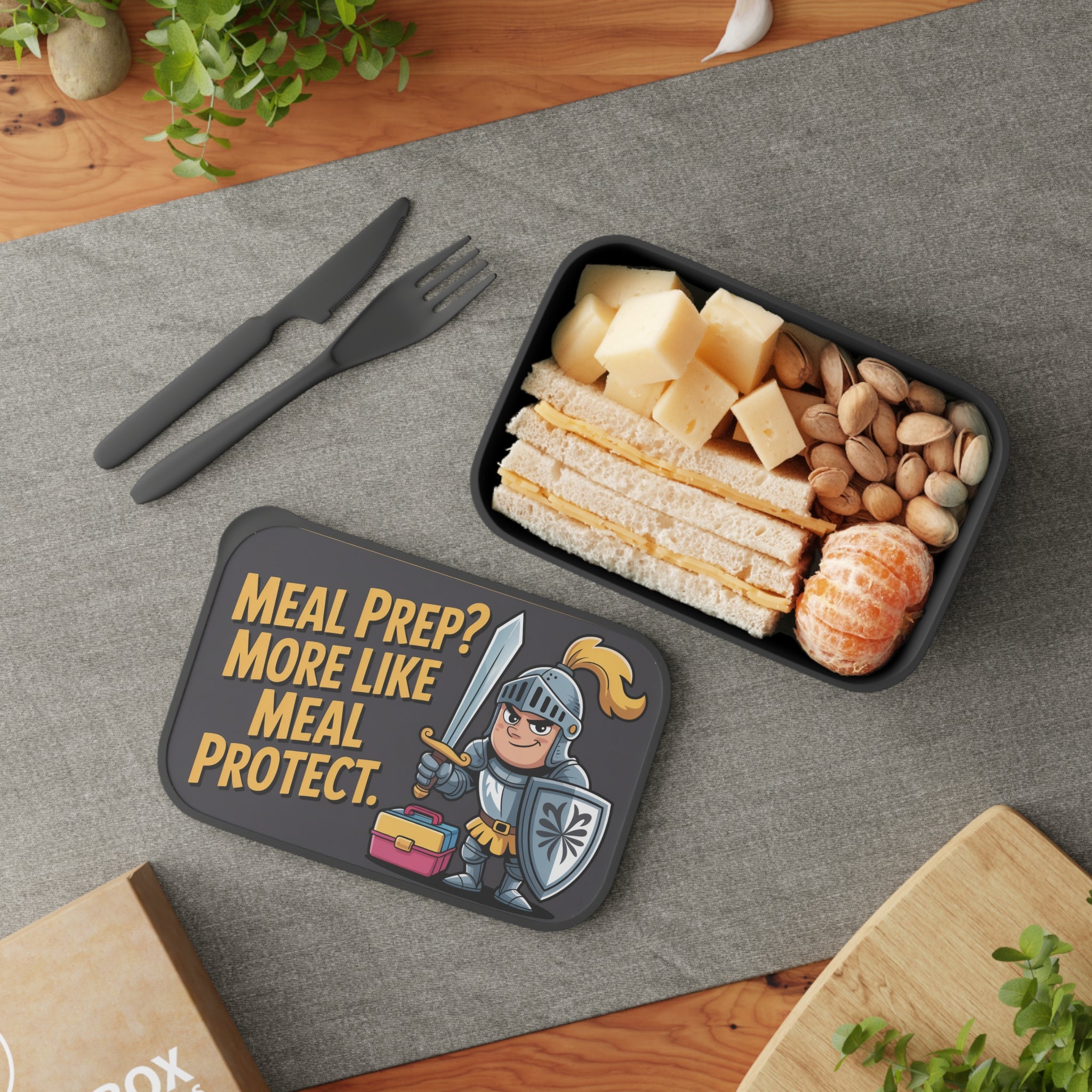 Black lunchbox with knight graphic, holding a sandwich, pistachios, and mandarin slices.