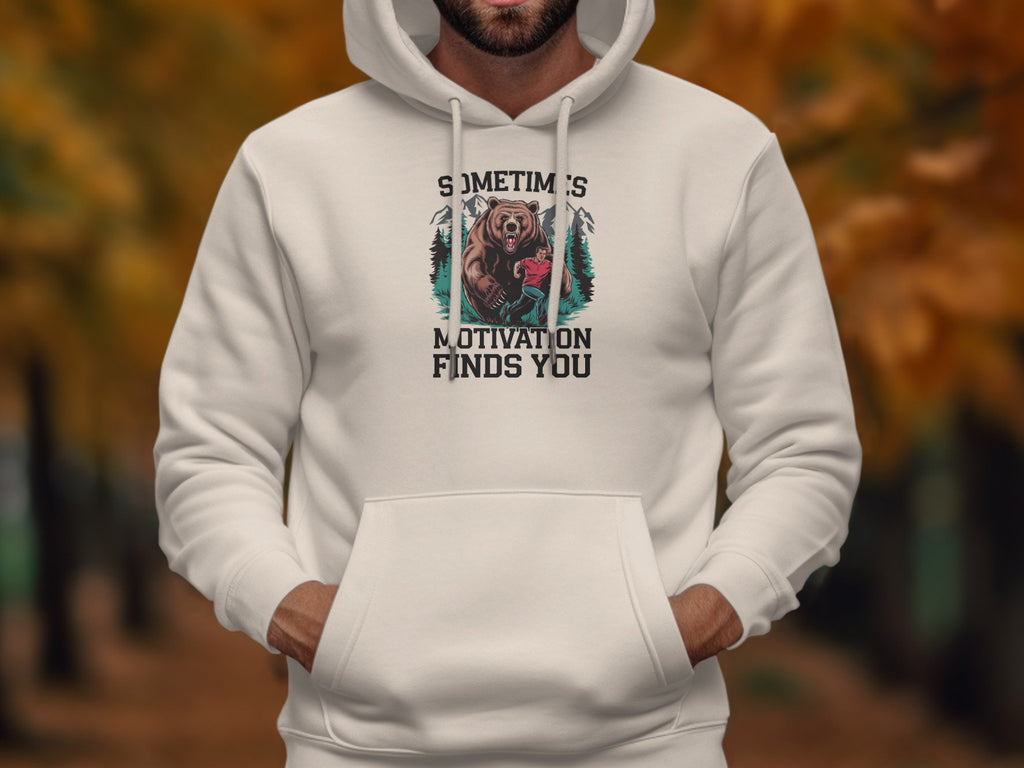White hoodie with graphic of a bear and person and text "Sometimes Motivation Finds You".
