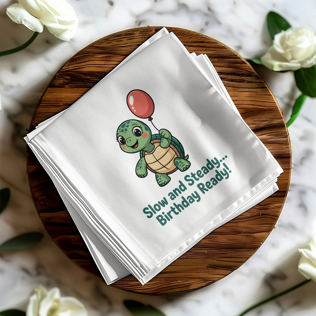Turtle with balloon, "Slow and Steady... Birthday Ready!" on folded white cloth.