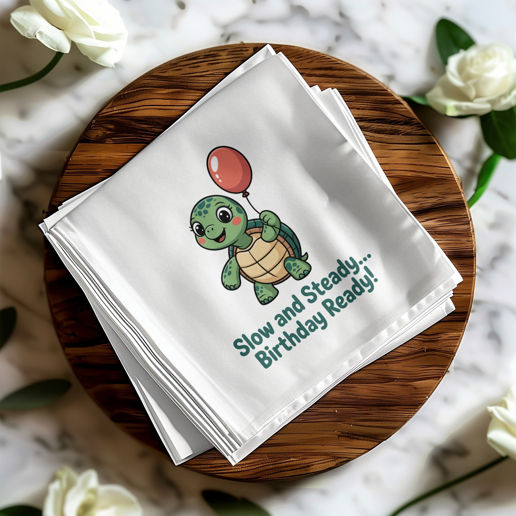 Turtle with balloon, "Slow and Steady... Birthday Ready!" on folded white cloth.