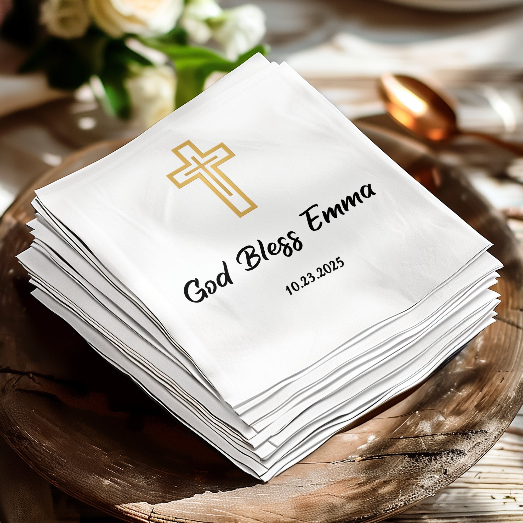 Stack of white napkins with gold cross and "God Bless Emma 10.23.2025".